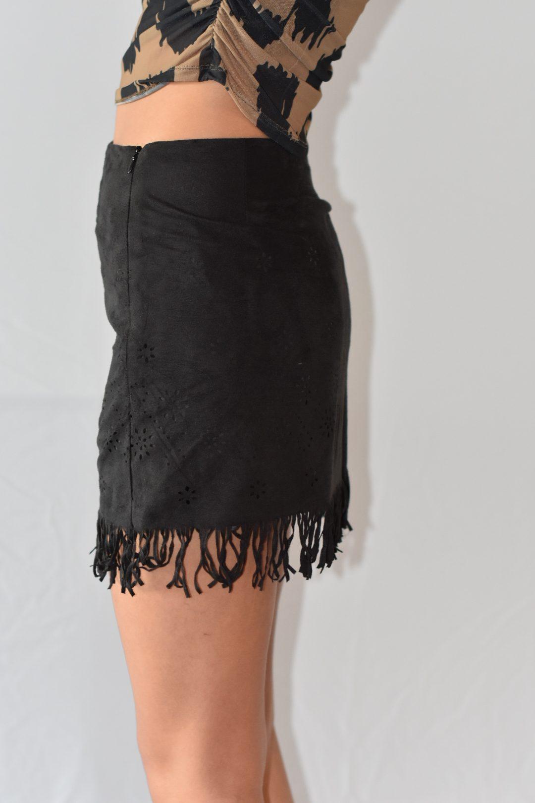 Mini falda ajustada en gamuza negra con detalles de flecos en el borde, perfecta para combinar con cualquier prenda en un estilo moderno
