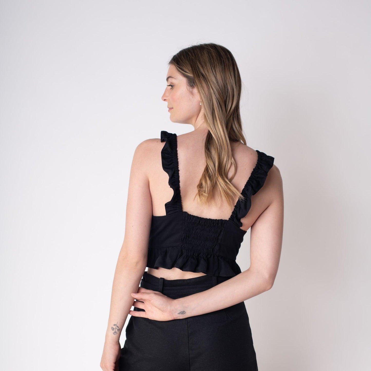 Blusa Marta Negra estilo crop top, con tirantes de volantes y lazo frontal, perfecta para realzar la figura con elegancia